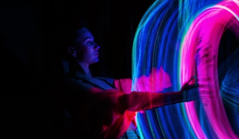 Person in front of a swirl of pink and blue light
