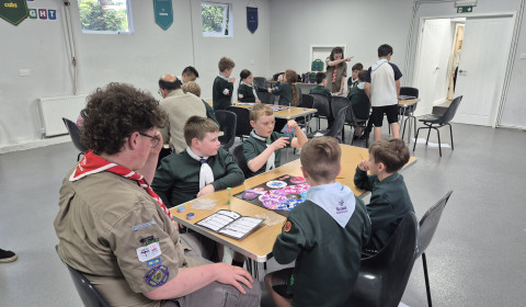 Groups of young Cubs sit around three tables playing boardgames