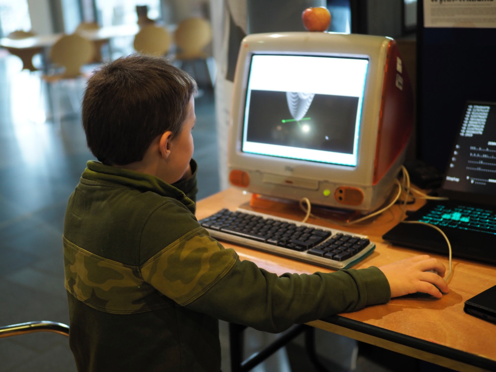 back of young boy at an older iMac computer
