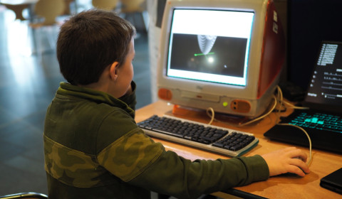 back of young boy at an older iMac computer