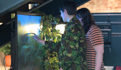 People taking part in an interactive digital activity on a large touchscreen display, exploring decision making, risk, and the factors that influence choices.