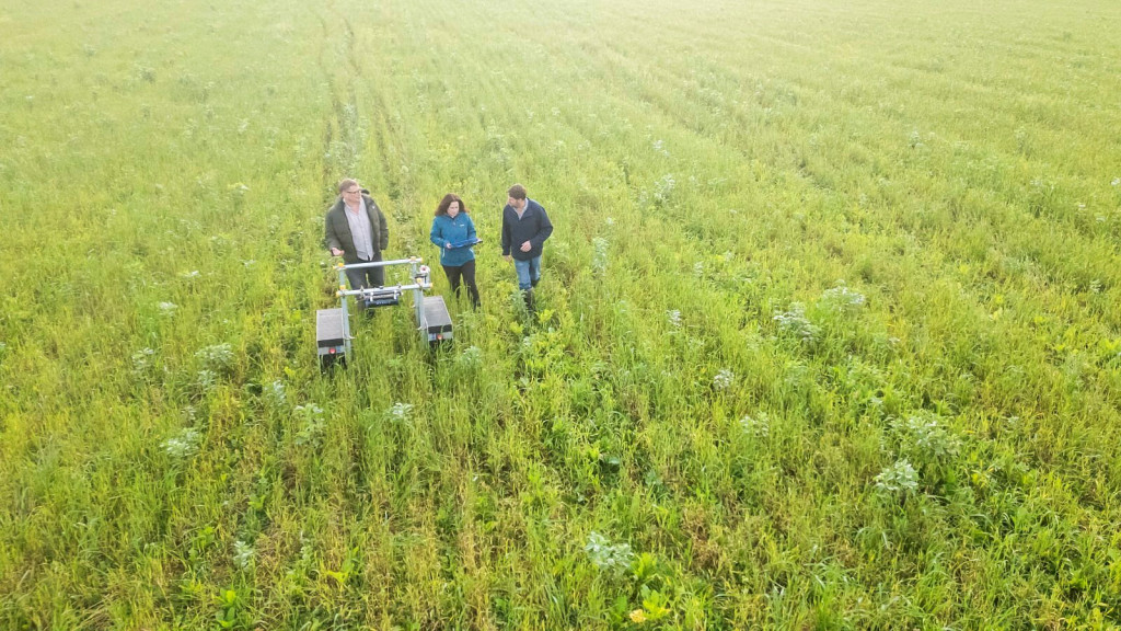 Aerial photograph of researchers standing in a field beside monitoring equipment, highlighting research into agriculture, food systems and food supply chain resilience.