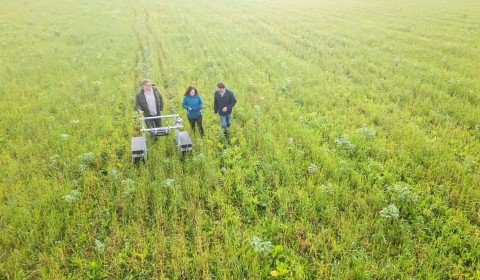 Aerial photograph of researchers standing in a field beside monitoring equipment, highlighting research into agriculture, food systems and food supply chain resilience.