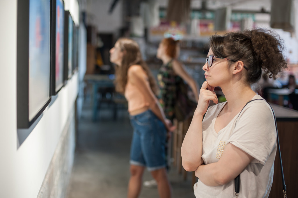 A person looking at a pictured frame on the wall