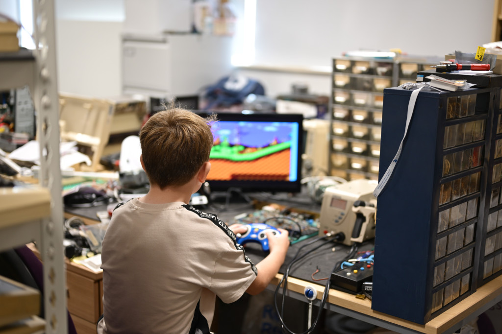 Young boy in lab, playing computer game on retro computer