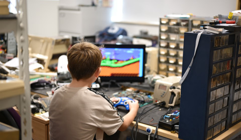 Young boy in lab, playing computer game on retro computer