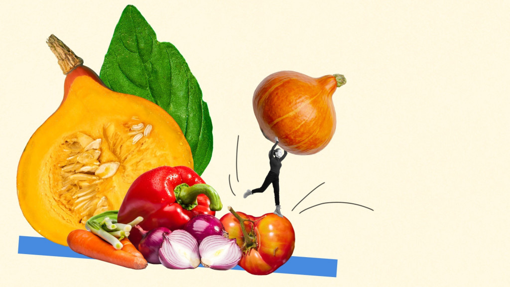 Collage art featuring a tiny monochrome person balancing on a giant tomato while lifting an orange squash over their head, next to an arrangement of fresh vegetables including a halved squash, bell pepper, carrots, and onions.