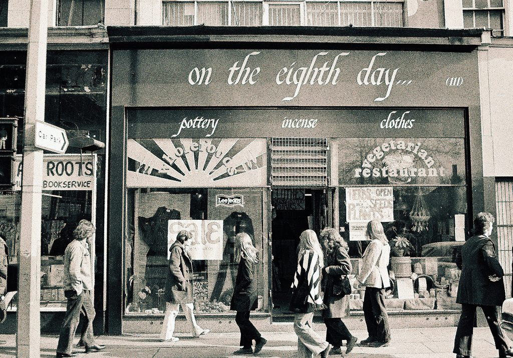Black and white photo of the shopfront of Eight Day Worker Co-operative with people walking past