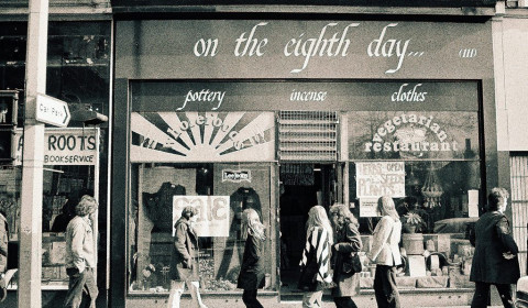 Black and white photo of the shopfront of Eight Day Worker Co-operative with people walking past