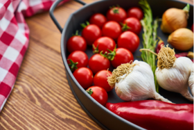 Cast iron pan with fresh ingredients including tomatoes, garlic, onions, chilli and thyme