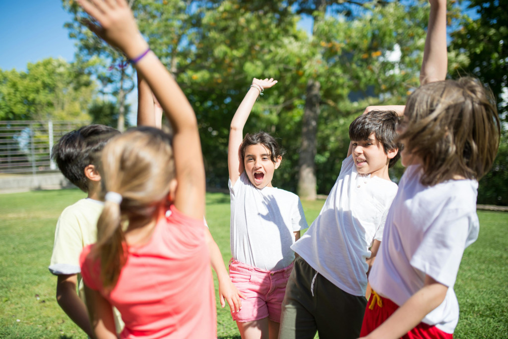 Five children raising their one hand in celebration, possibly to do a combined high five