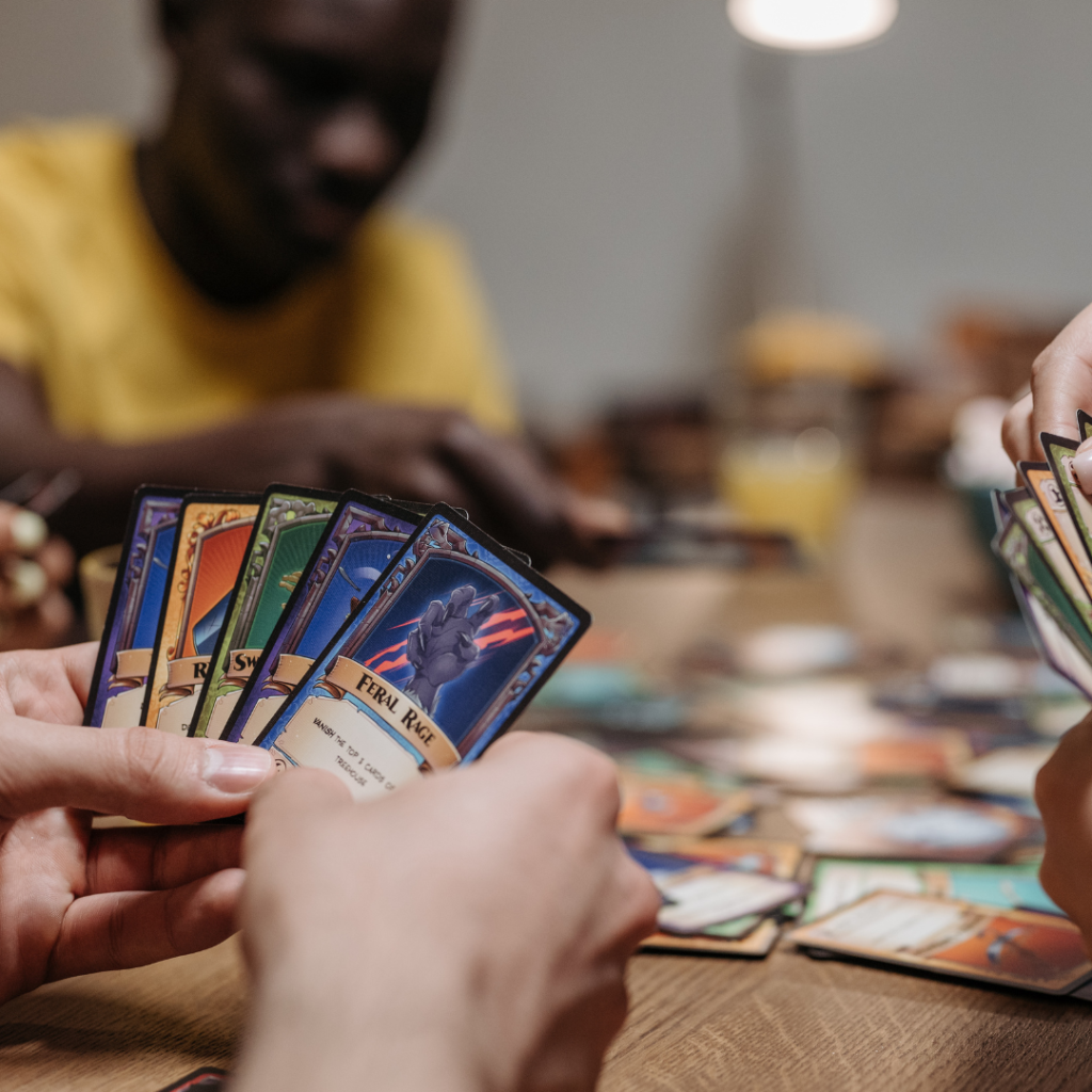 An image of three people sat around a table playing a card game.