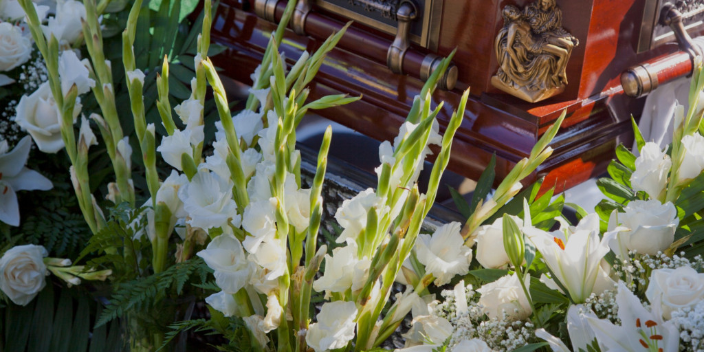 Photograph of a coffin surrounded by white flowers