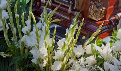 Photograph of a coffin surrounded by white flowers