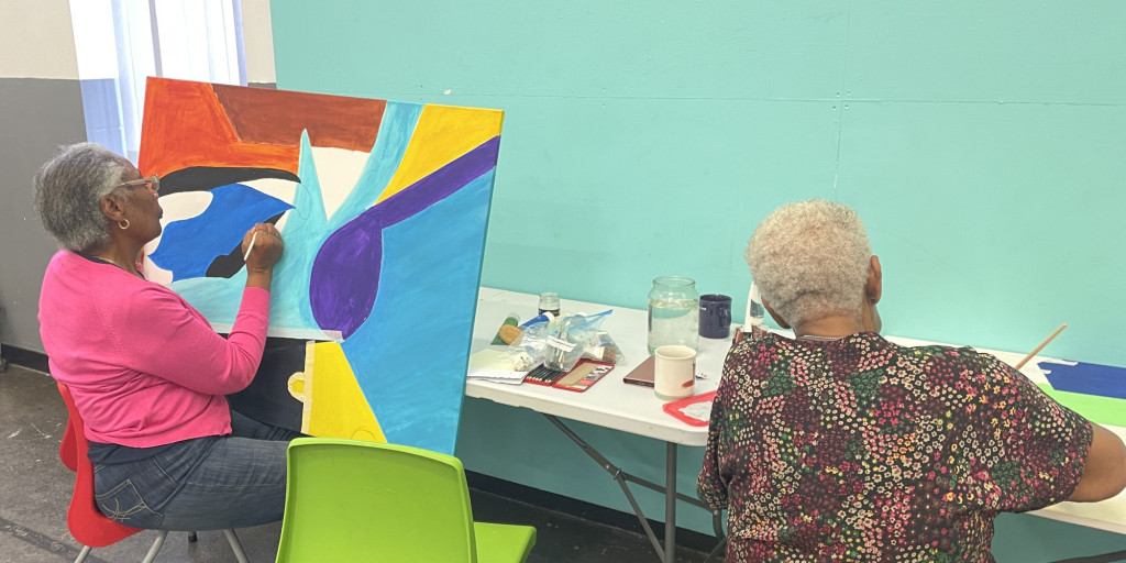 Photograph of two older women painting pictures