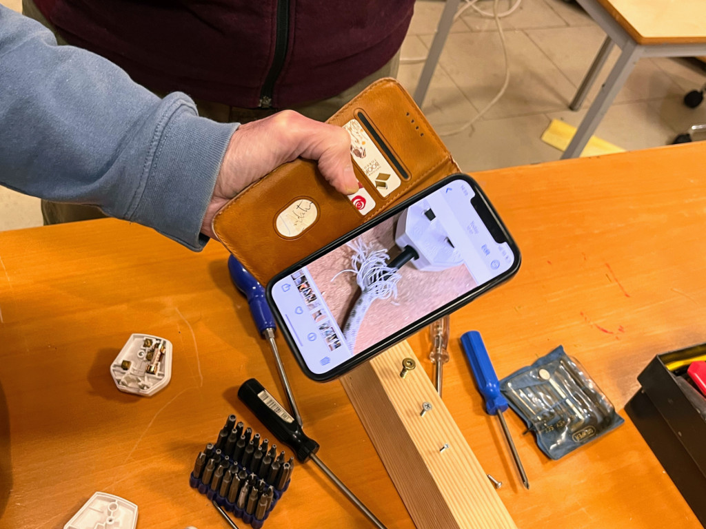 Person holding their phone over broken electrical equipment