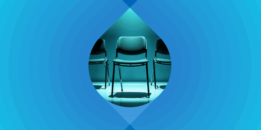 Photograph of a row of office chairs on a blue background. One chair is in a spotlight.