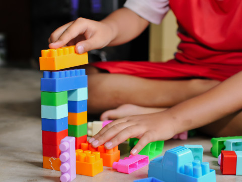 The picture shows a child playing with colourful building blocks.