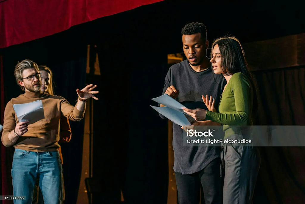 Photograph of four performers interacting on a stage.