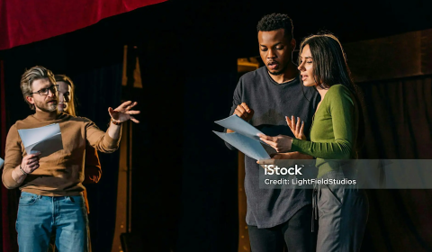 Photograph of four performers interacting on a stage.