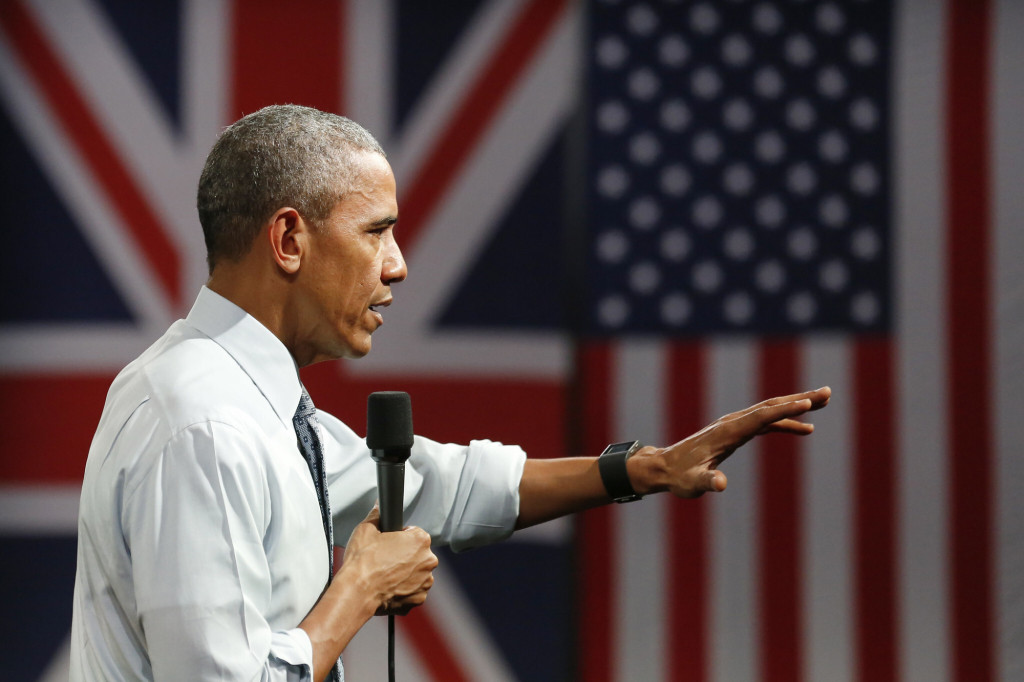 An image of Obama presenting at a Town Hall in front of a British and American Flag from the US Embassy London.