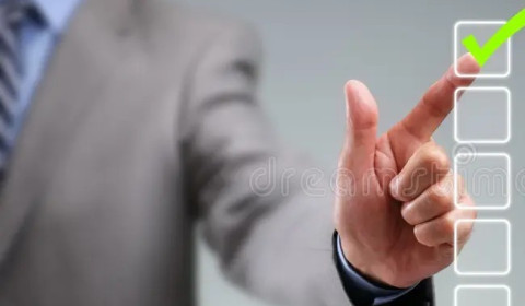 A formally dressed man wearing a suit and tie is selecting a tick box with his hand.