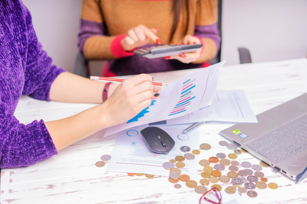 Two women reviewing financial documents and money together at a desk.