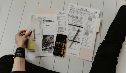 Image of an individual looking at tax returns and finances with a calculator on their phone