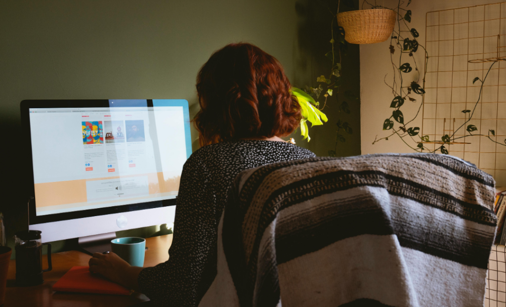 An image of a woman sitting at a desk and looking at a website