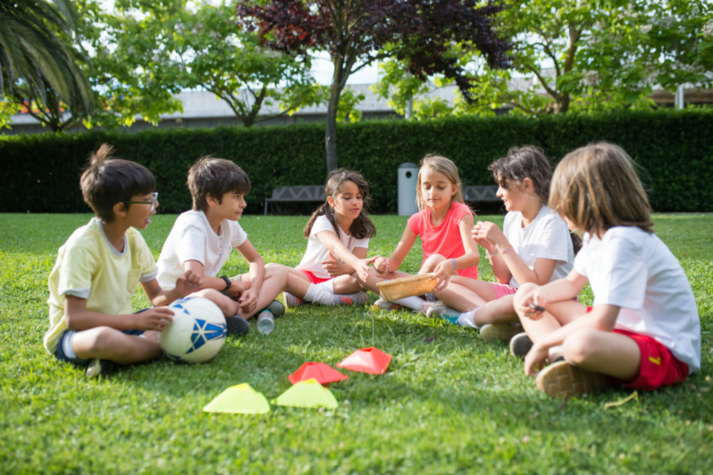 Photograph of children sitting on the grass outdoors