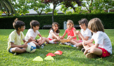 Photograph of children sitting on the grass outdoors