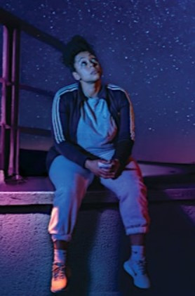Image shows a girl sat looking at the night sky