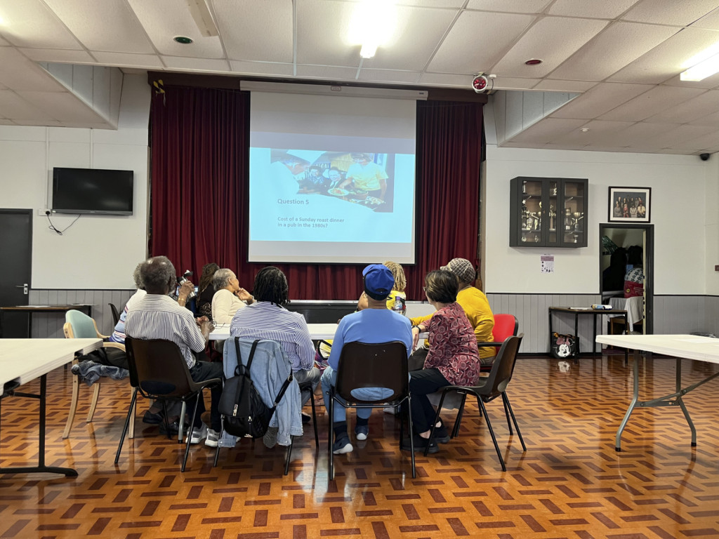 Photo of participants at an event sitting in a circle in front of a presentation screen