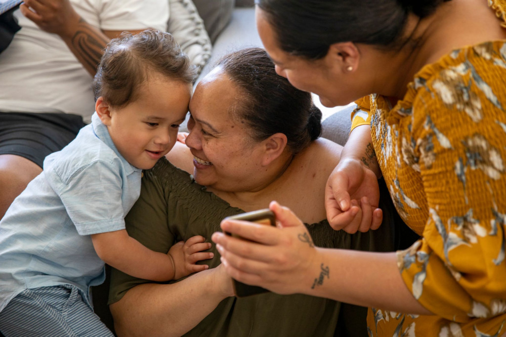 Child and caregiver looking at a mobile telephone.