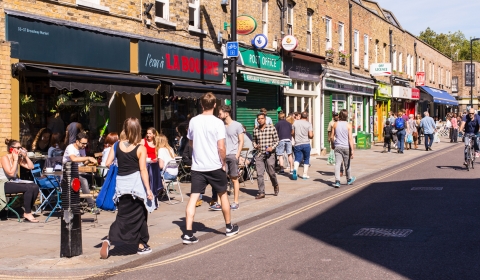 Typical high street scene with row of shops and cafes and pedestrians walking on the pavement