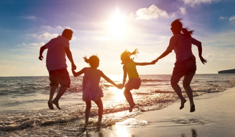 The picture shows a family jumping up in the air on a beach.