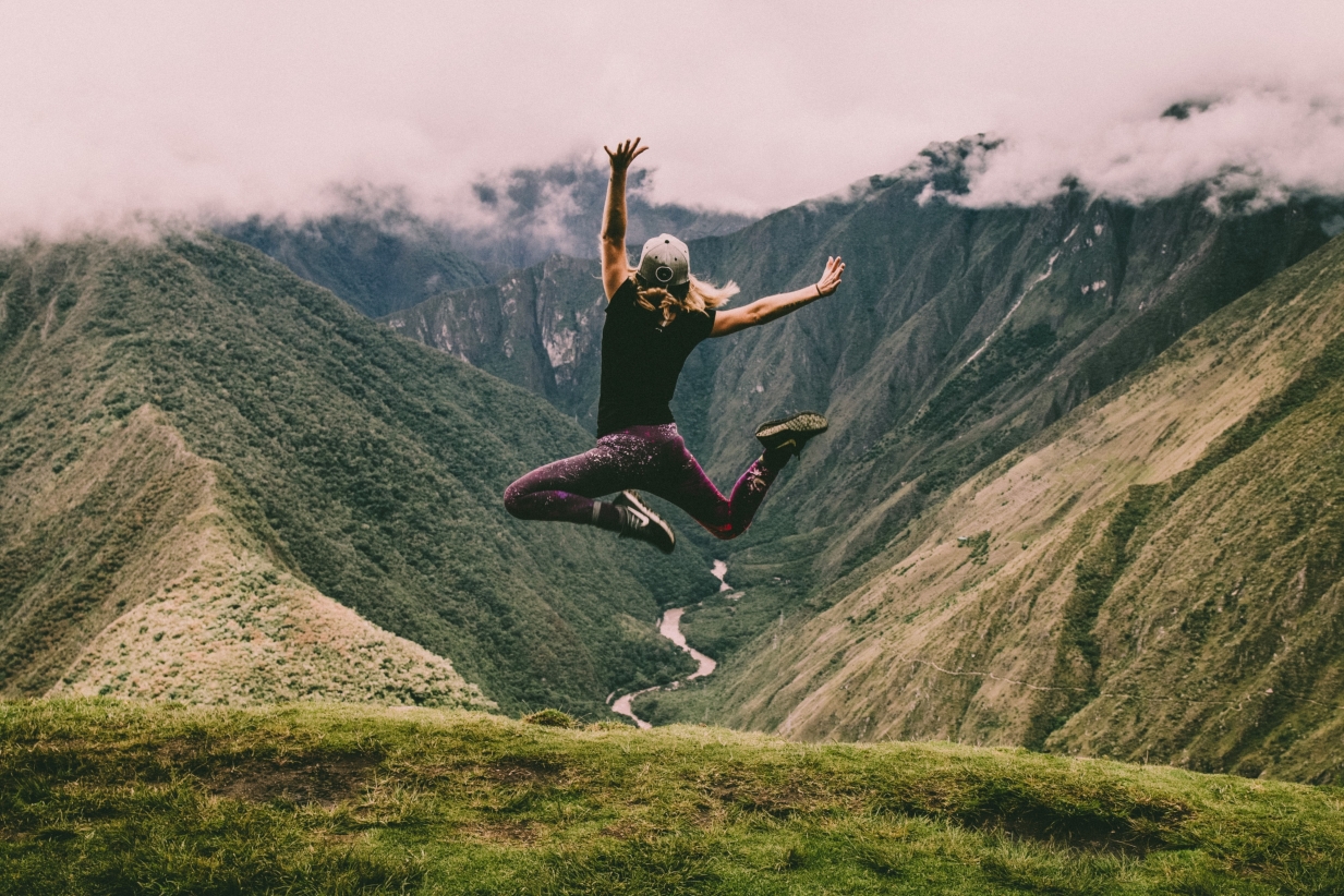 Person jumpoing with mountains in the background