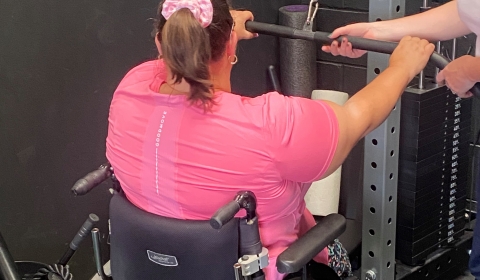 Female in wheelchair lifting weights.