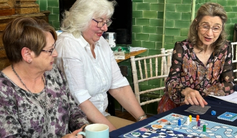 Three women enjoying the dementia care board game.