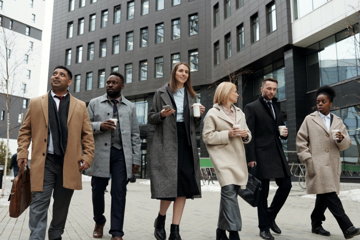 A group of professionals in smart clothing walk by a city building