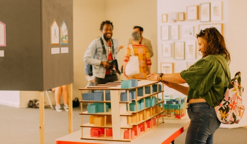A group of three people looking at an exhibition featuring architectural models.