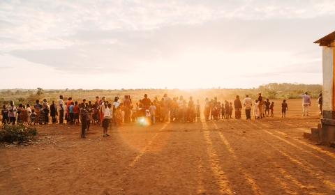a photo of a community in Malawi with the sun setting in the background