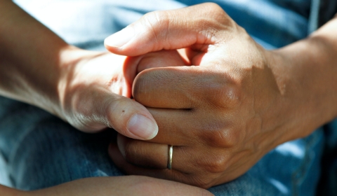 A close up image of two people holding hands.