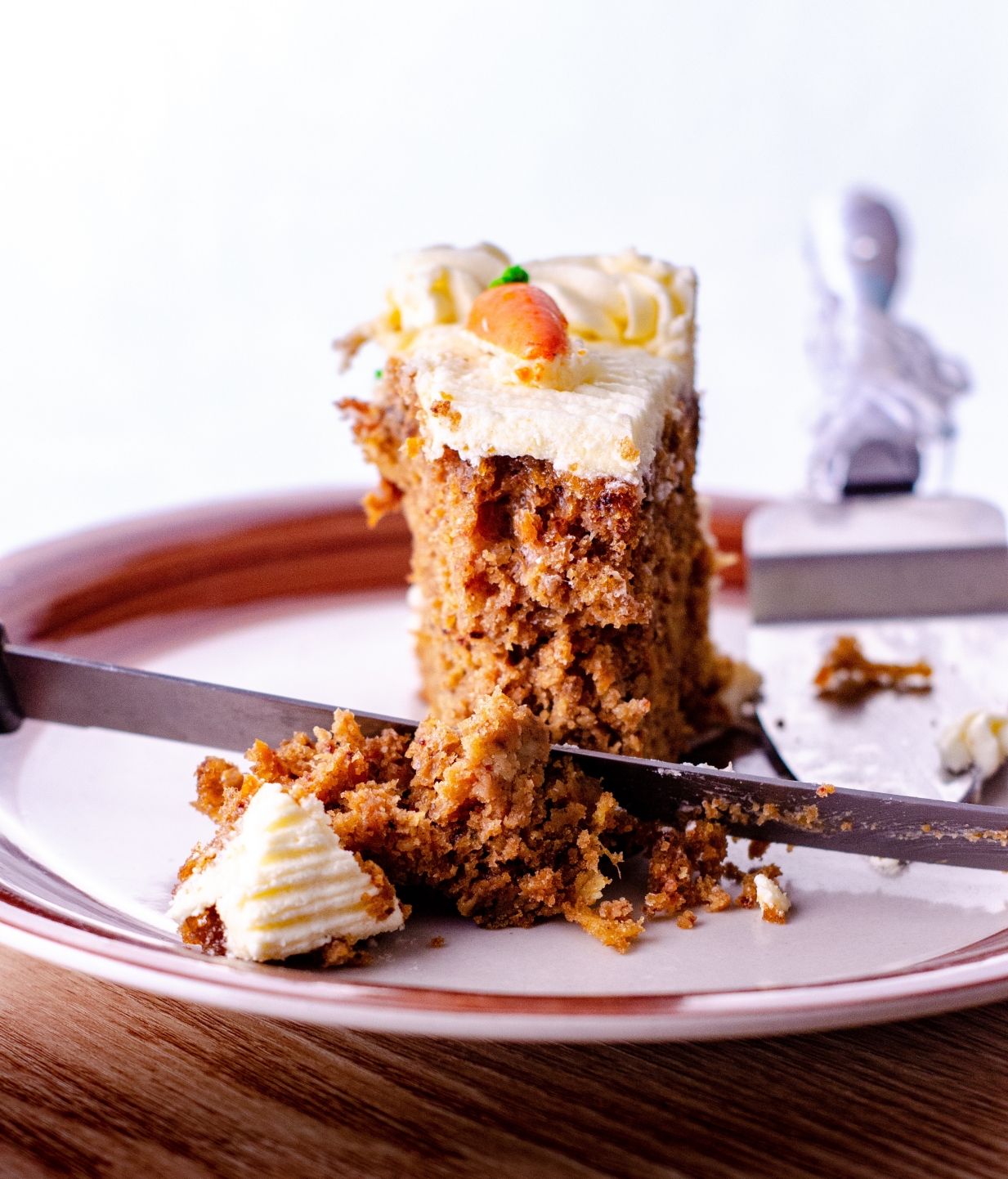 A photograph of a slice of frosted carrot cake on a plate.