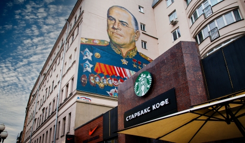 A photo of a Russian military mural with a starbucks sign in the foreground