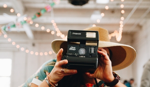 Person in a hat taking a Polaroid picture